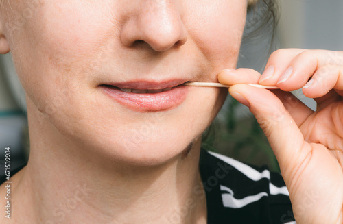 Dental and oral hygiene. A woman holds a toothpick in her mouth. Close-up