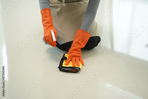 A young Asian woman is mopping the tile floor in the living room while cleaning the house while at home taking time to take care of her daily routine.
