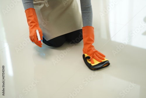 A young Asian woman is mopping the tile floor in the living room while cleaning the house while at home taking time to take care of her daily routine.