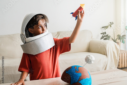 Astronaut child dreams of travel in space with crafty rocket ship at home - Happy boy playing and exploring galaxy photo