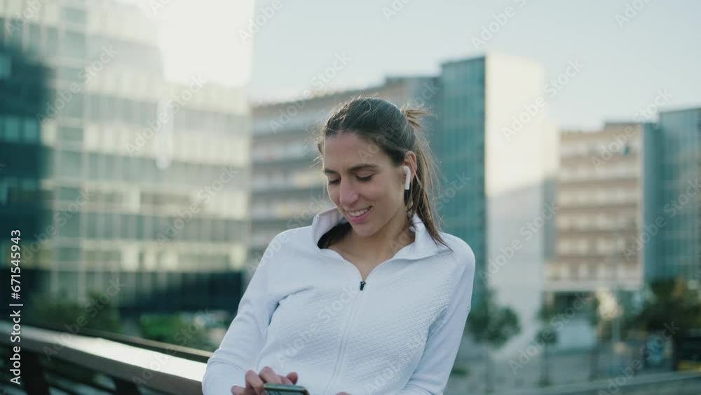 Young athlete wearing earphones reading on smartphone Young athlete wearing earphones reading on smartphone