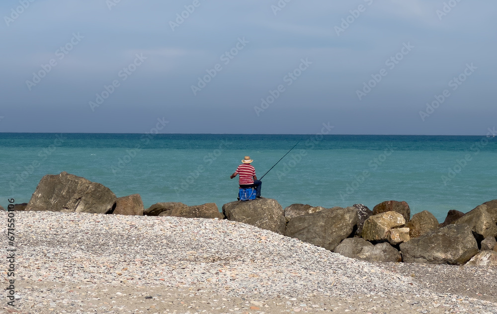 Fisherman catches fish on coast near sea. Catching fish in sea from shore. Fishing by sea. Catching fish on spinning at ocean from shore. Fisherman catches fish on coast near sea. Catching fish in sea from shore. Fishing by sea. Catching fish on spinning at ocean from shore.