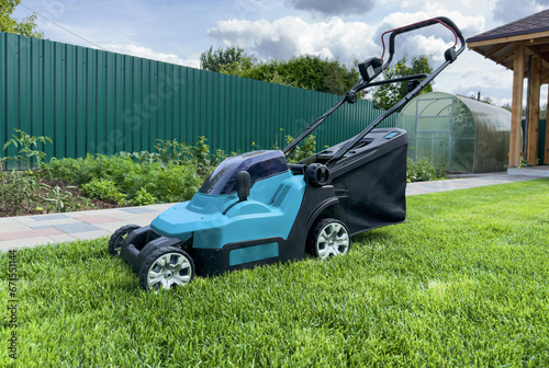 Lawn Mower Electric for cutting grass in garden. Сutting grass in yard using Lawn Mower. Lawn mowing machine. Grass Trimmer and Grass Cutter. Lawn maintenance service. Gardener mows weeds