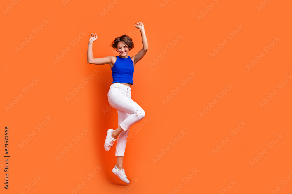 Full body portrait of gorgeous cheerful lady jumping raise hands empty space ad isolated on orange color background