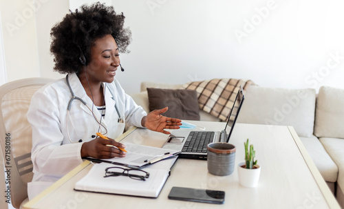 Medicine, online service and healthcare concept - African American female doctor or nurse with headset, clipboard and laptop at hospital.