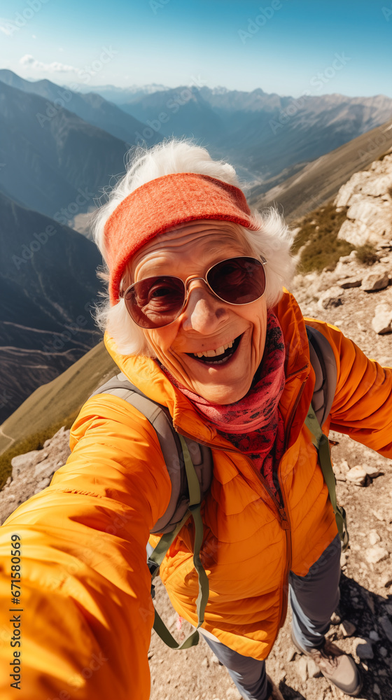 Happy senior woman hiker taking selfie with mobile phone on mountain peak