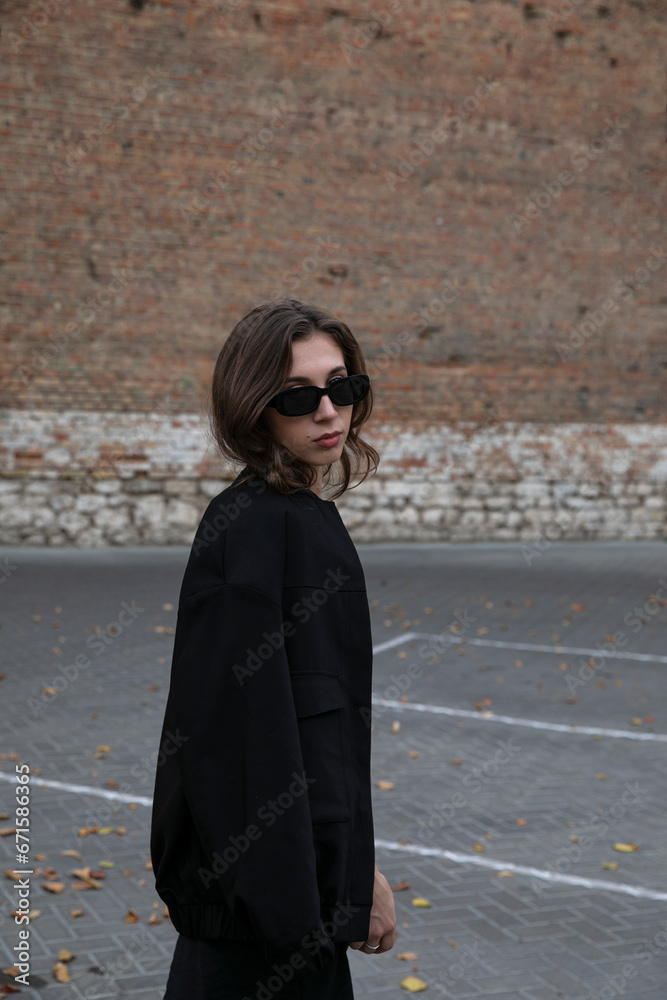 Profile image of an attractive female model in sunglasses, all black outfit.