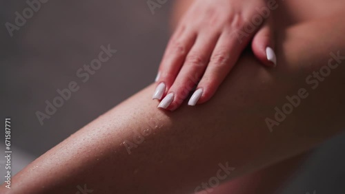 Woman touches hair on leg ankle closeup