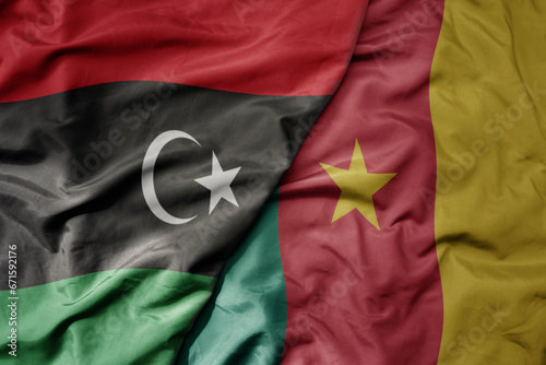 big waving national colorful flag of libya and national flag of cameroon .