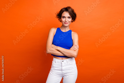Photo of cool confident lady wear blue singlet smiling arms crossed isolated orange color background