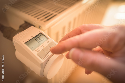 Zum Energiesparen wird elektronisches Thermostat an Heizung auf 18,5 Grad Raumtemperatur eingestellt photo