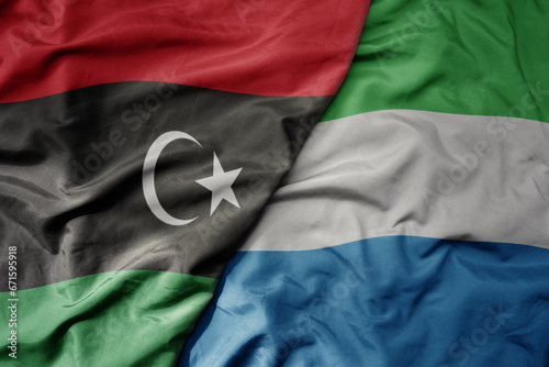big waving national colorful flag of libya and national flag of sierra leone .