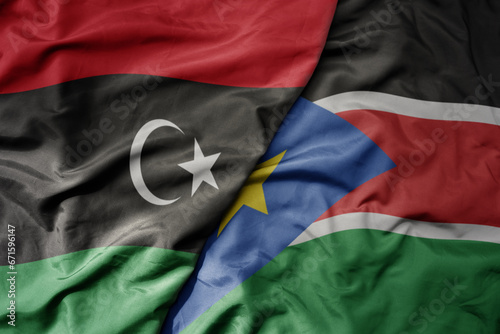 big waving national colorful flag of libya and national flag of south sudan .