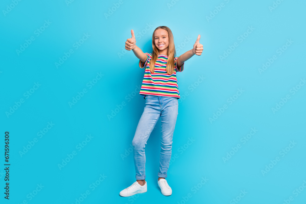Full length photo of good mood schoolgirl dressed striped t-shirt jeans showing thumbs up to you isolated on blue color background