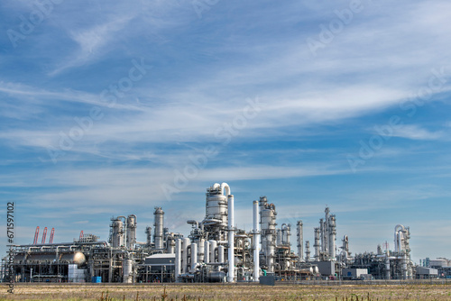 Panoramic view of a chemical plant or refinery with fractioning or distillation towers, boilers and pipes for oil and chemicals against a blue sky