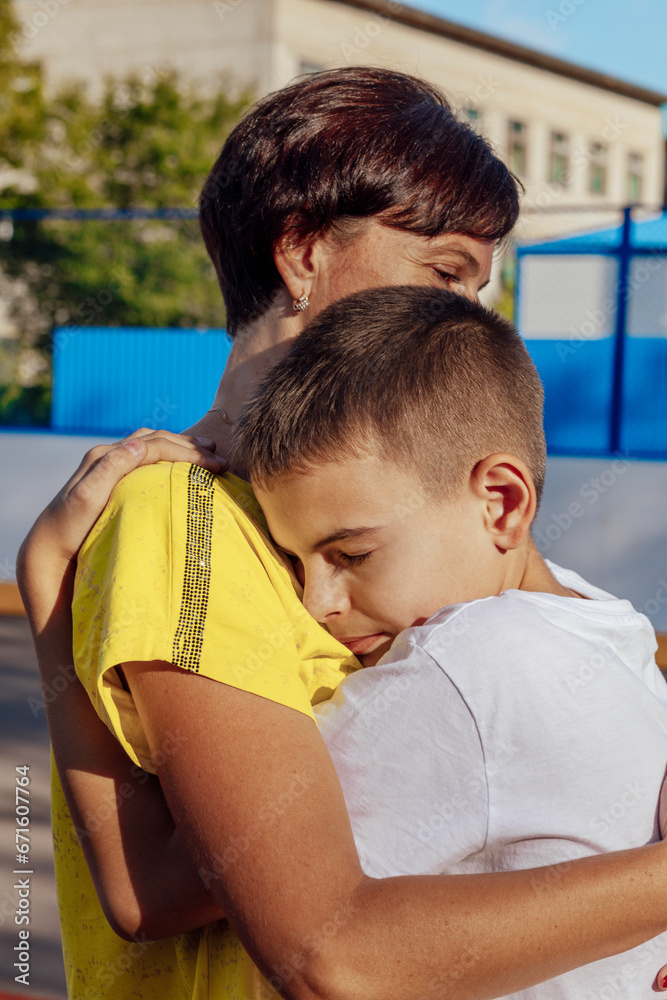 Outdoor Hugs: A Mother and Teen Daughter Share a Tender Cuddle in the Sun on a sports cord Outdoor Hugs: A Mother and Teen Daughter Share a Tender Cuddle in the Sun on a sports cord