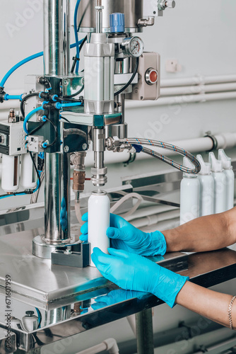 Women's hands fill tin cans for aerosols with cosmetics at the factory