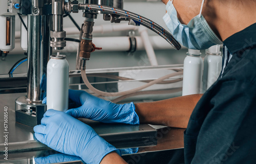 Unrecognizable woman in a mask, cap and gloves works in the production of cosmetics or a pharmaceutical company