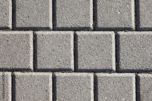 Cobblestone pavement. Square shape bricks. Gray walking path. Paved texture. Street tile background.