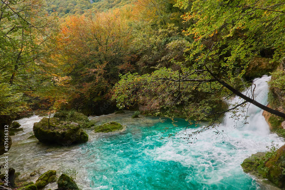 The waterfalls and crystal clear, blue, turquoise and green waters of the Nacedero del Urederra, with its beech forest with its autumn colors in the Sierra de Urbasa-Andía. Navarre. Spain The waterfalls and crystal clear, blue, turquoise and green waters of the Nacedero del Urederra, with its beech forest with its autumn colors in the Sierra de Urbasa-Andía. Navarre. Spain