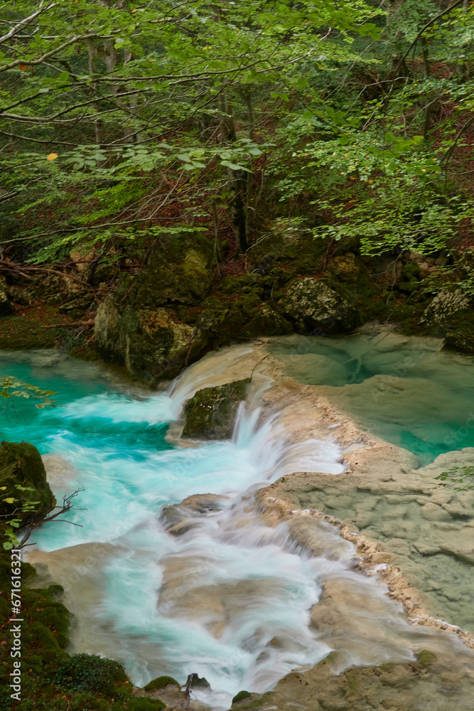 The waterfalls and crystal clear, blue, turquoise and green waters of the Nacedero del Urederra, with its beech forest with its autumn colors in the Sierra de Urbasa-Andía. Navarre. Spain The waterfalls and crystal clear, blue, turquoise and green waters of the Nacedero del Urederra, with its beech forest with its autumn colors in the Sierra de Urbasa-Andía. Navarre. Spain