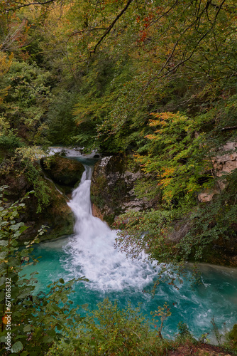 Fototapeta Naklejka Na Ścianę i Meble -  The waterfalls and crystal clear, blue, turquoise and green waters of the Nacedero del Urederra, with its beech forest with its autumn colors in the Sierra de Urbasa-Andía. Navarre. Spain