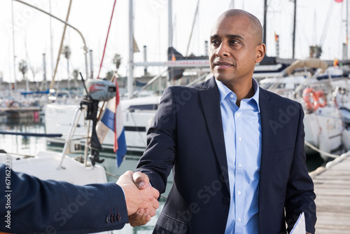 Two men in suits buy and sell a yacht in the seaport