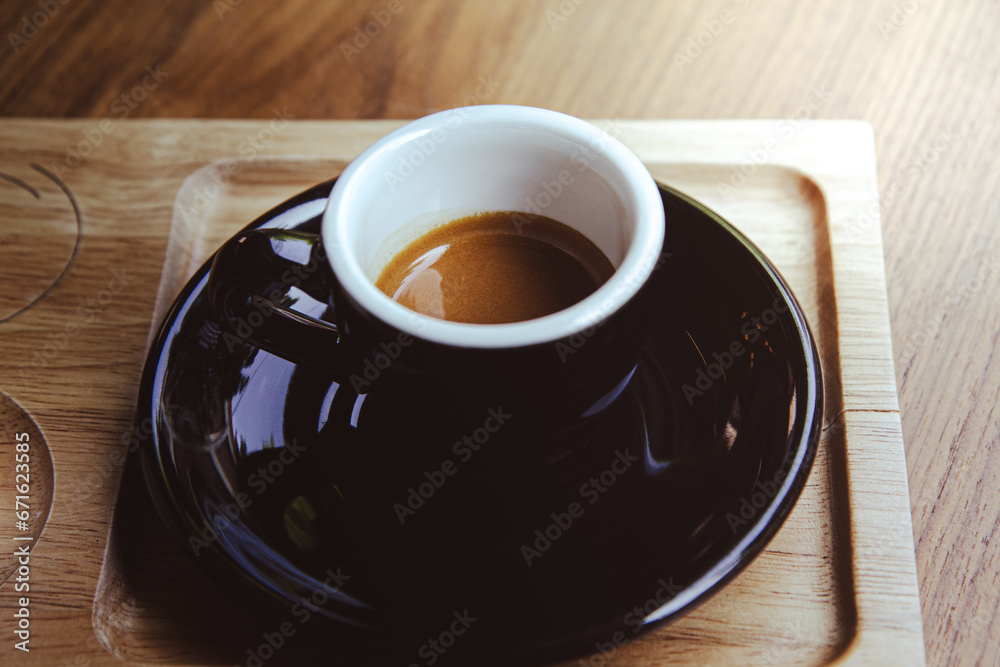 Obraz premium High angle of cup of hot aromatic espresso placed on black saucer over wooden table.