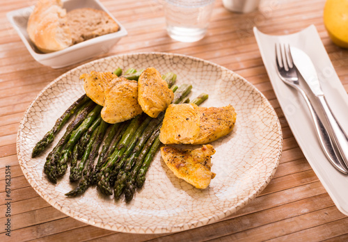 Fried chicken breast pieces with asparagus on white plate