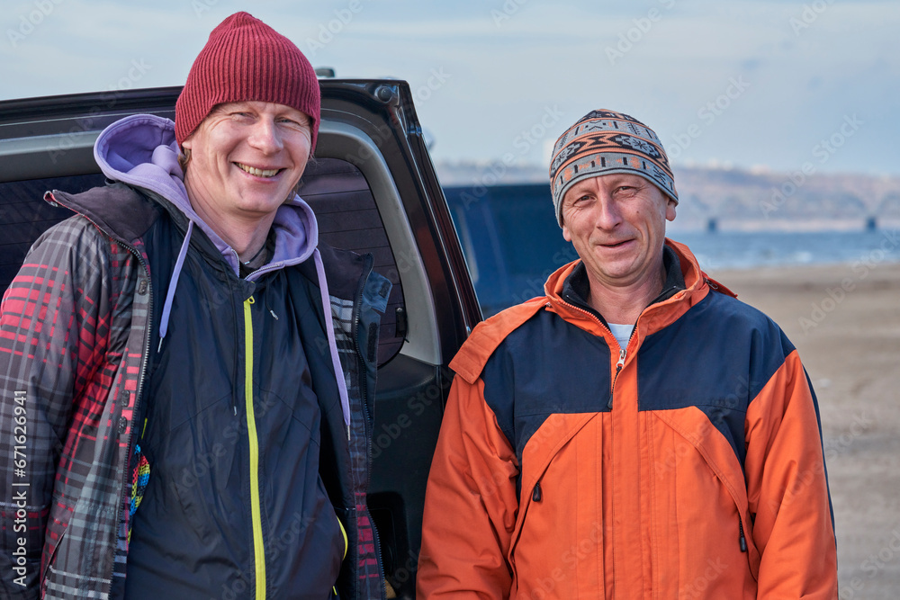 Mature men stand on the sandy shore and relax. A break between kitesurfing. Mature men stand on the sandy shore and relax. A break between kitesurfing.