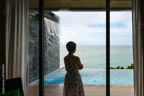 Happy senior digital nomad woman relaxing stand at luxury pool villa near beach, Phuket Thailand.