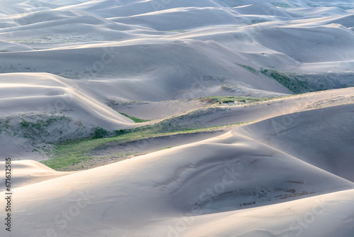 Close up view of sand dunes at golden hour and sunset at Great Sand Dunes National Park in Colorado on a sunny summer evening, with mountains in the background
