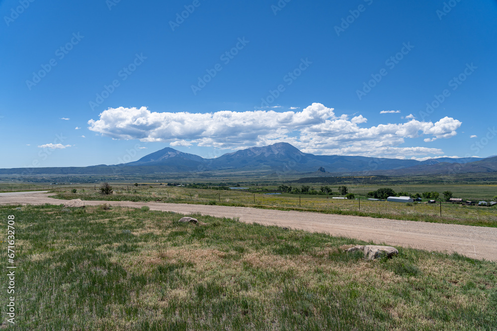 Fototapeta premium A road leading to Great Sand Dunes National Park in Colorado on a sunny summer day, with mountains in the background
