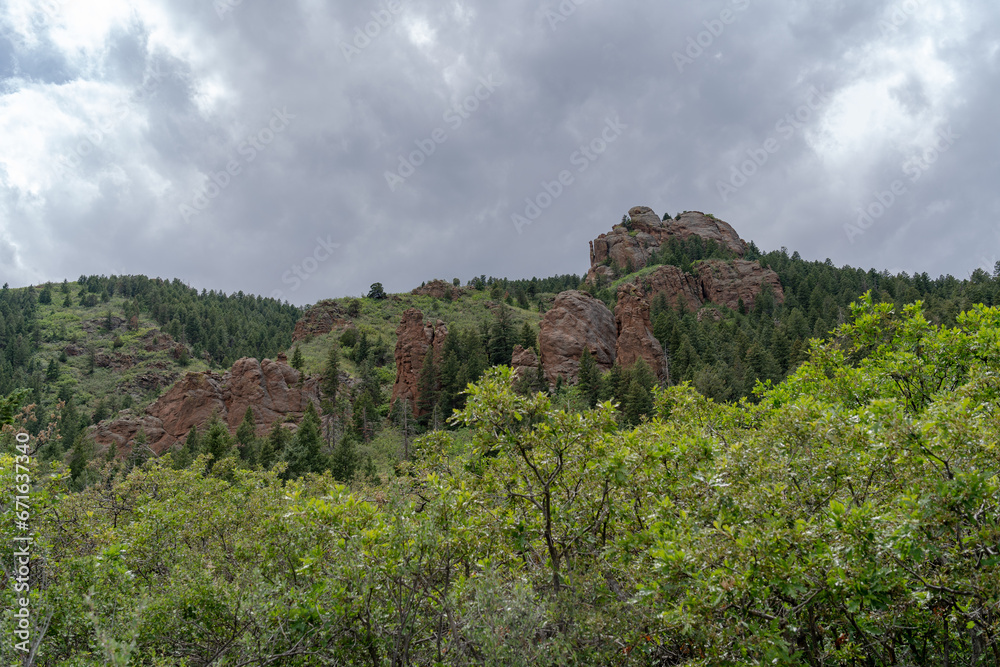 View of mountains, trees, and red rocks from Section 16 and Palmer Loop Hiking Trail in Colorado Spring, CO on a cloudy and overcast summer day