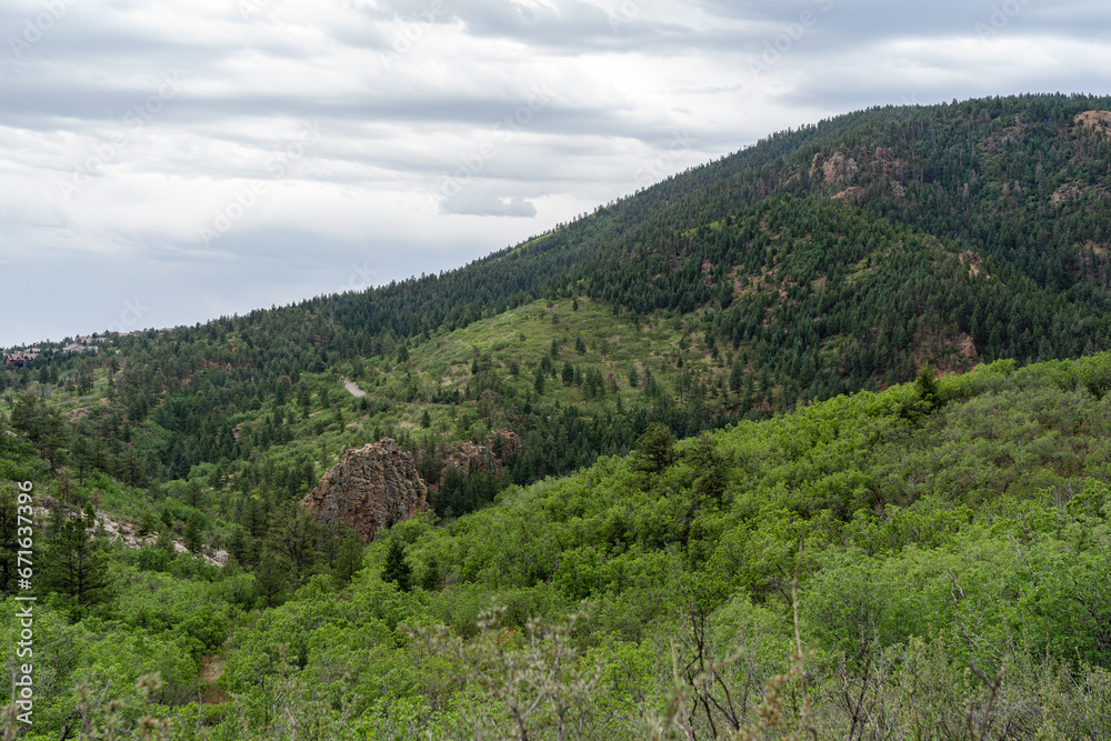 View of mountains, trees, and red rocks from Section 16 and Palmer Loop Hiking Trail in Colorado Spring, CO on a cloudy and overcast summer day
