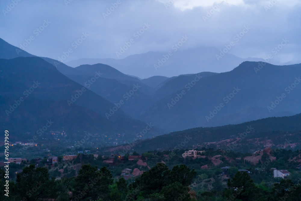 A view of a rainstorm over Pike's Peak and other blue misty mountains on a cloudy summer evening, as viewed from Garden of the Gods in Colorado Springs, CO