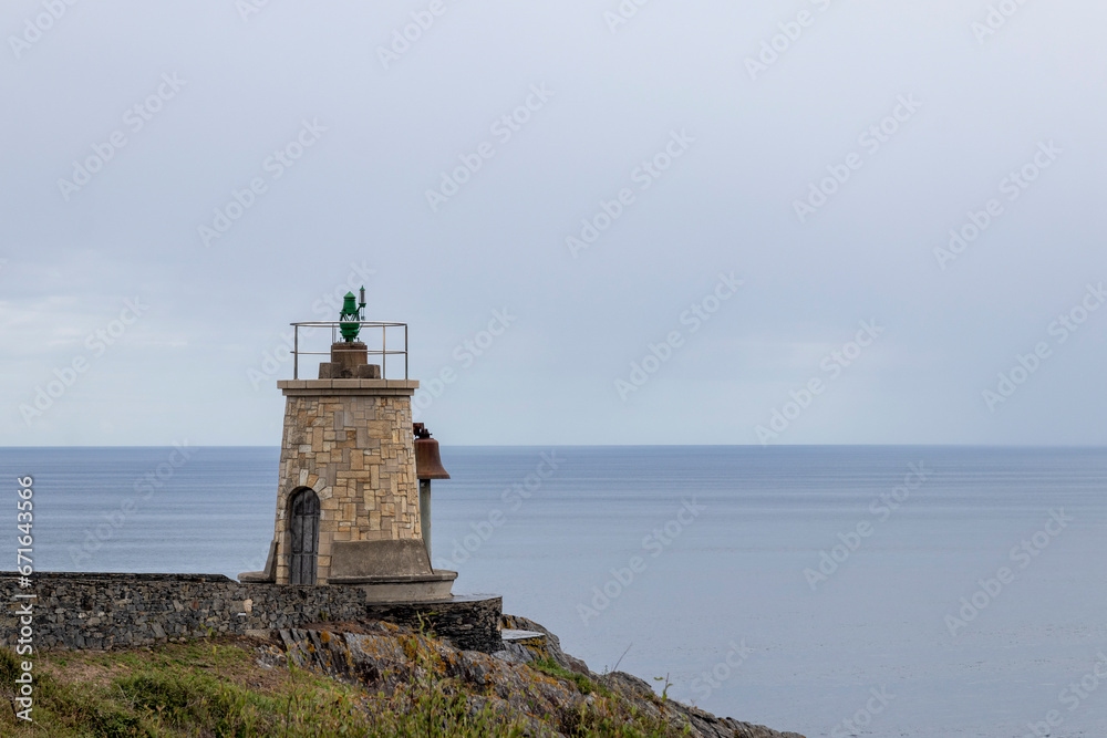 A Beacon of Light: A Stone Lighthouse Overlooking the Ocean on a Cloudy Day