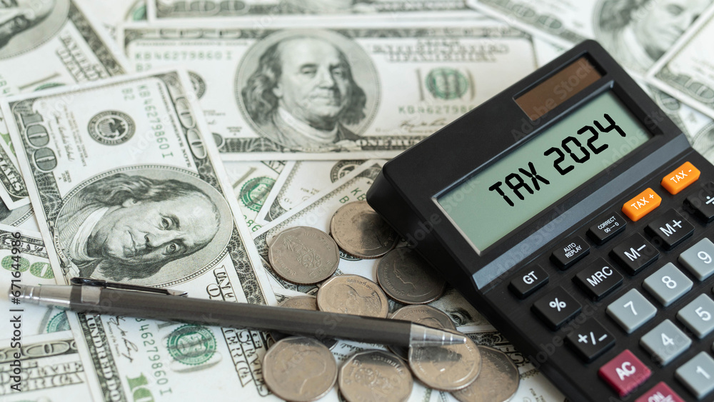 Fototapeta premium Tax 2024. Word Tax 2024 on calculator. Business and tax concept. Calculator, currency, dollar bills close up. Income Statement. paying the tax rate. Taxation, investment, taxes burden.