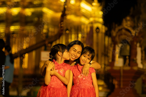 Happy family, mother and her children pose for the camera at Golden pagoda at Wat Phra That Haripunchai Woramahawihan in Lamphun, north of Thailand.