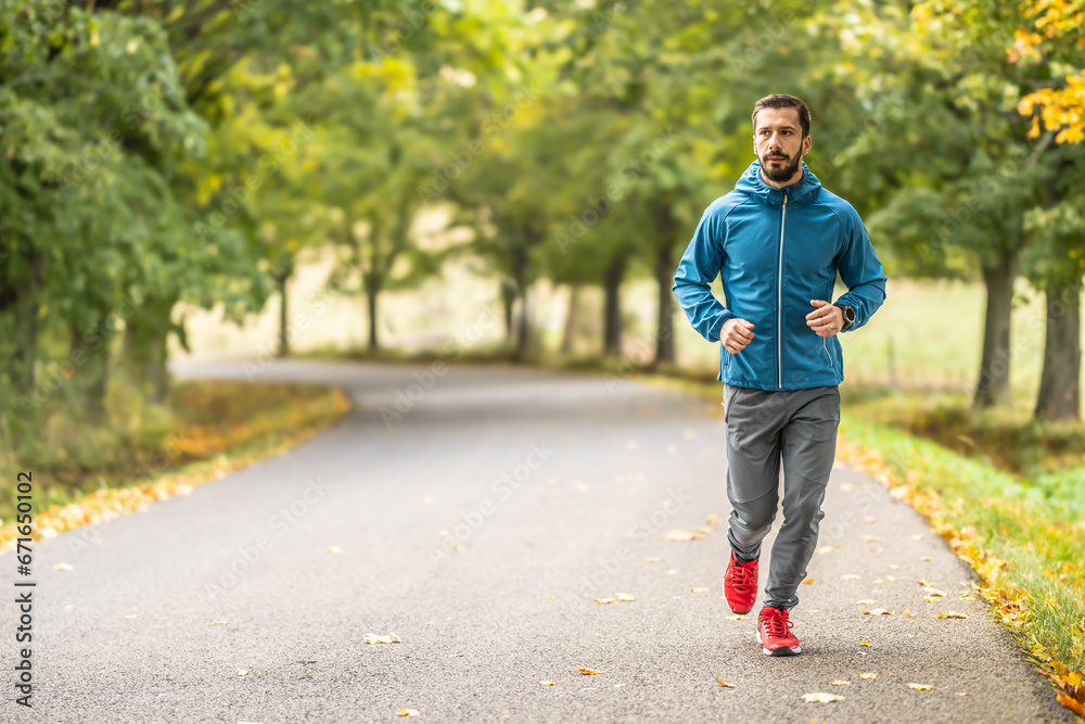 Obraz premium A young man is training and running in an autumn park.