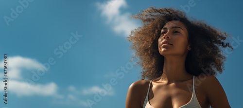 Young black woman looking at sunny blue sky