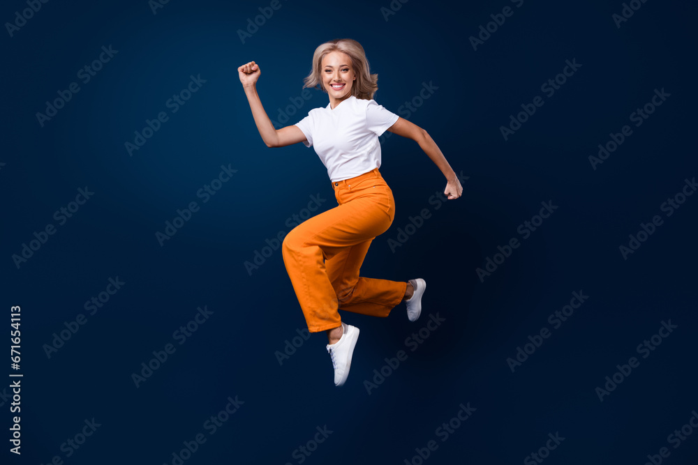 Full length photo of charming cheerful girl dressed trendy outfit running going fast isolated on dark blue color background Full length photo of charming cheerful girl dressed trendy outfit running going fast isolated on dark blue color background