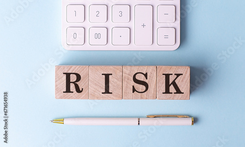 RISK on wooden cubes with pen and calculator, financial concept