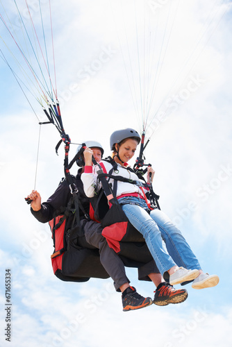 People, paragliding and happy in sky, together or extreme sport with freedom for fitness. Coach, partnership and person on adventure, helmet or fearless with backpack, parachute or flight with clouds