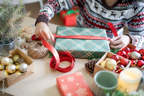 Woman in knitted sweater wrapping christmas presents with eco paper girl packing christmas gifts Xmas holiday concept