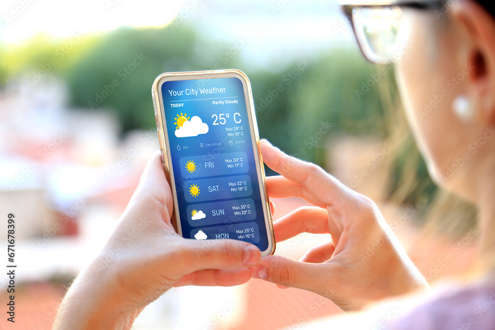 Woman outdoors checking weather forecast on her smartphone. - obrazy, fototapety, plakaty 