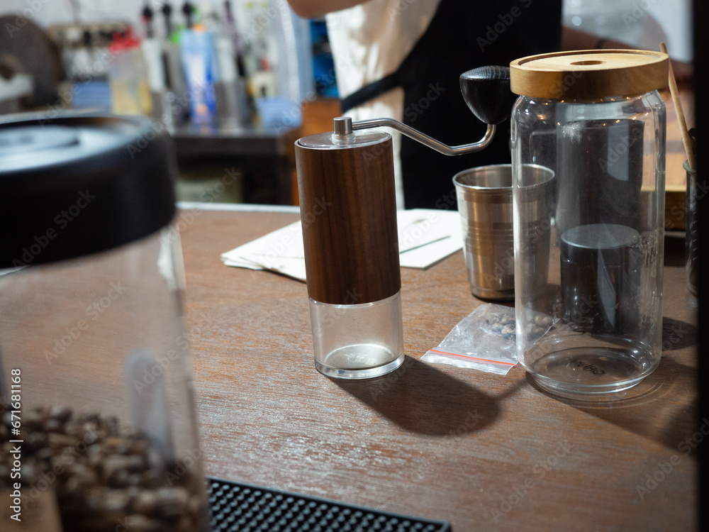 manual coffee grinder on the table surrounded by coffee storage and coffee processing tools manual coffee grinder on the table surrounded by coffee storage and coffee processing tools