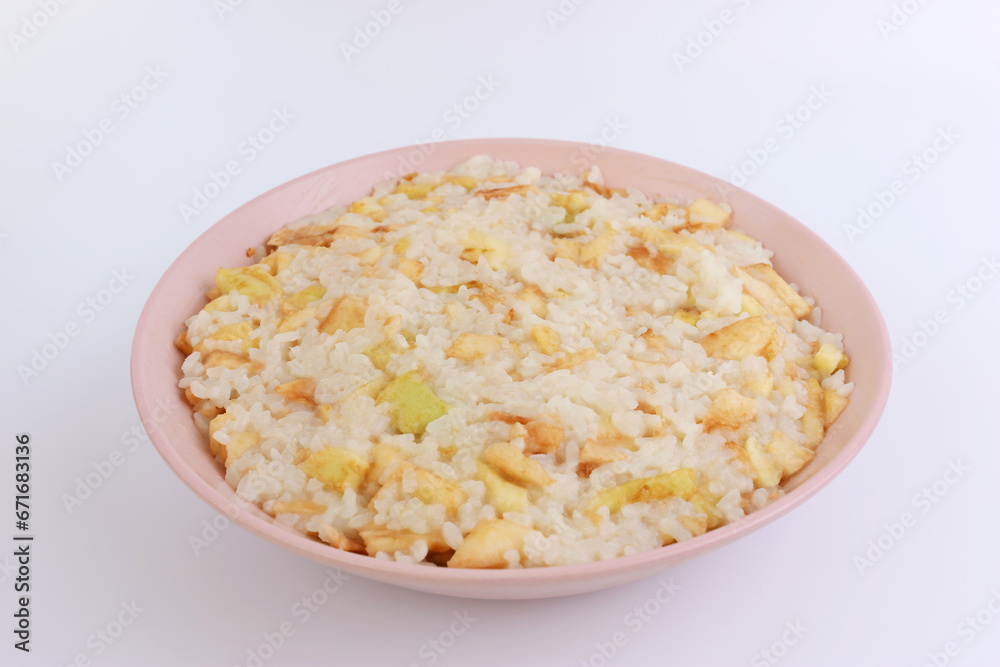 Rice porridge with apples in a pink bowl on a white background. Rice porridge with apples in a pink bowl on a white background.