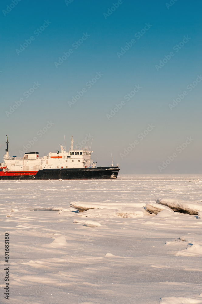 Winter shipping. Big cargo ship in ice sea fairway
