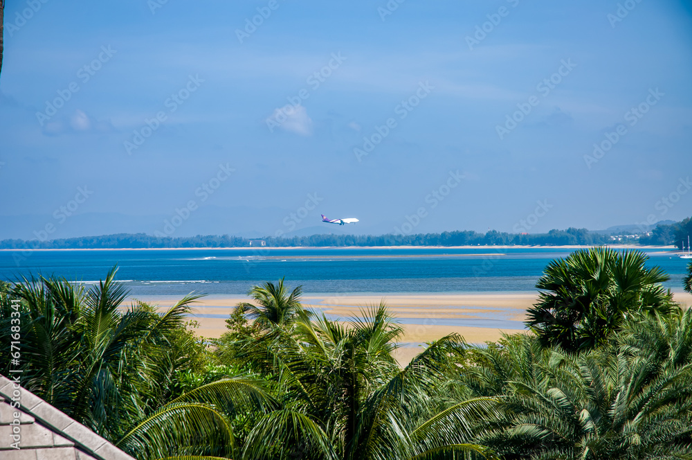 A plane landing over the ocean near the island of Phuket